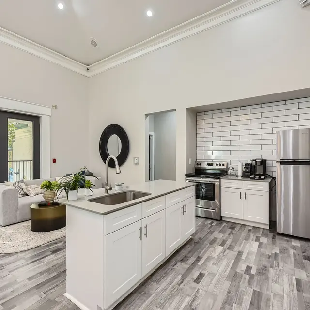Interior view of a modern kitchen and living room with a gray color scheme and sleek appliances.