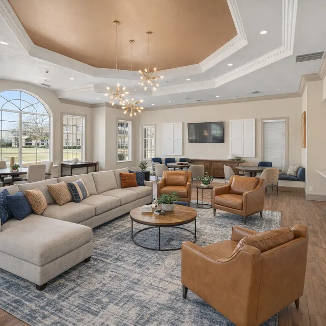 Modern Living Room Design A spacious and elegantly designed living room featuring a large sectional sofa, two brown armchairs, and a round coffee table on a patterned rug. The room has bright windows and a decorative ceiling with a chandelier.
