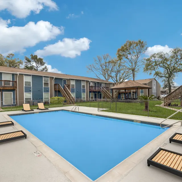 A tranquil pool area surrounded by apartment buildings and greenery on a sunny day.