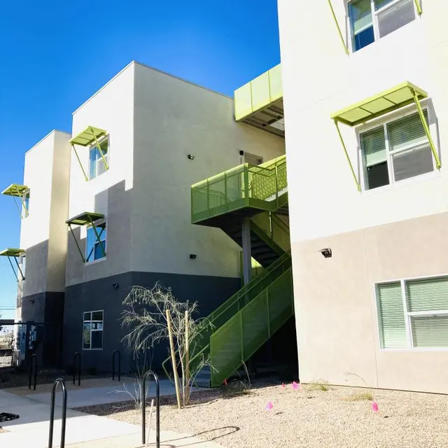 Modern Apartment Building A modern multi-level apartment building with a unique design featuring light-colored walls and green accents, including a staircase and window awnings.
