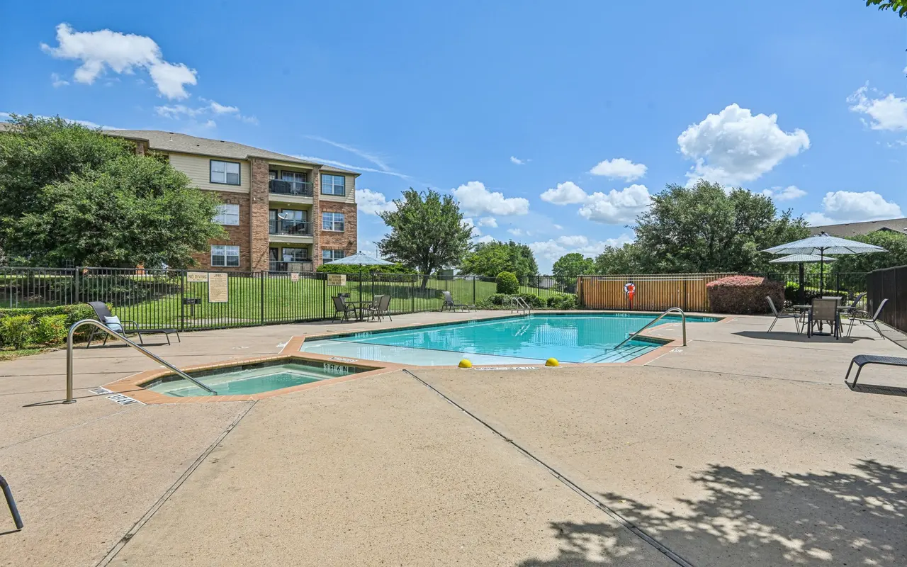 Sunny apartment pool area with lounge chairs and umbrellas