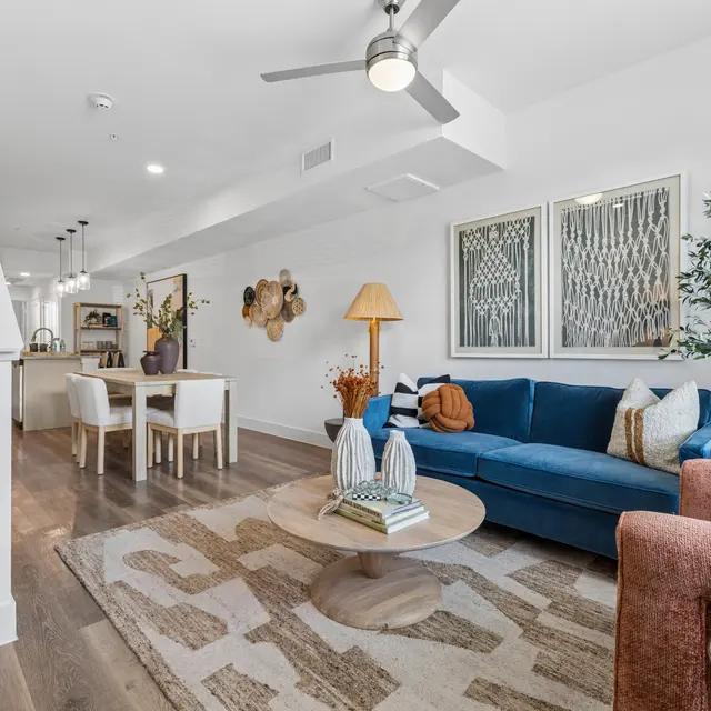Modern Living Room Design A modern living room featuring a blue sofa, orange armchair, round coffee table, and decorative elements in a bright space with a staircase in the background.
