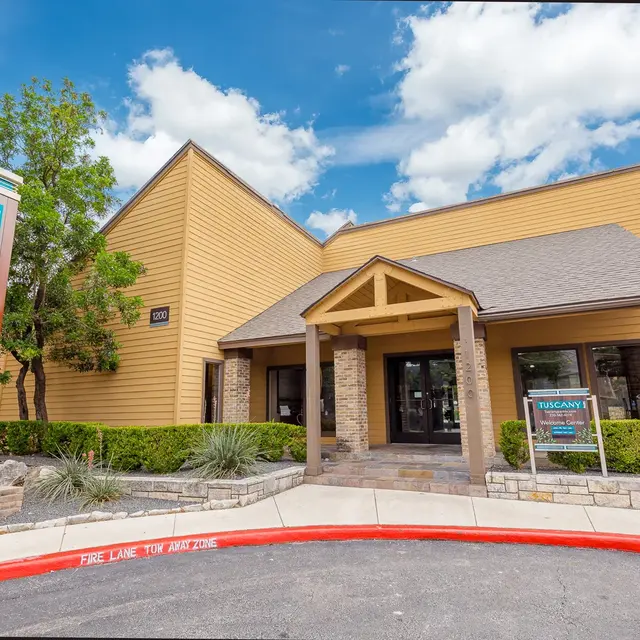 Exterior view of the Tuscany Park office building, featuring wooden architecture and a prominent sign.