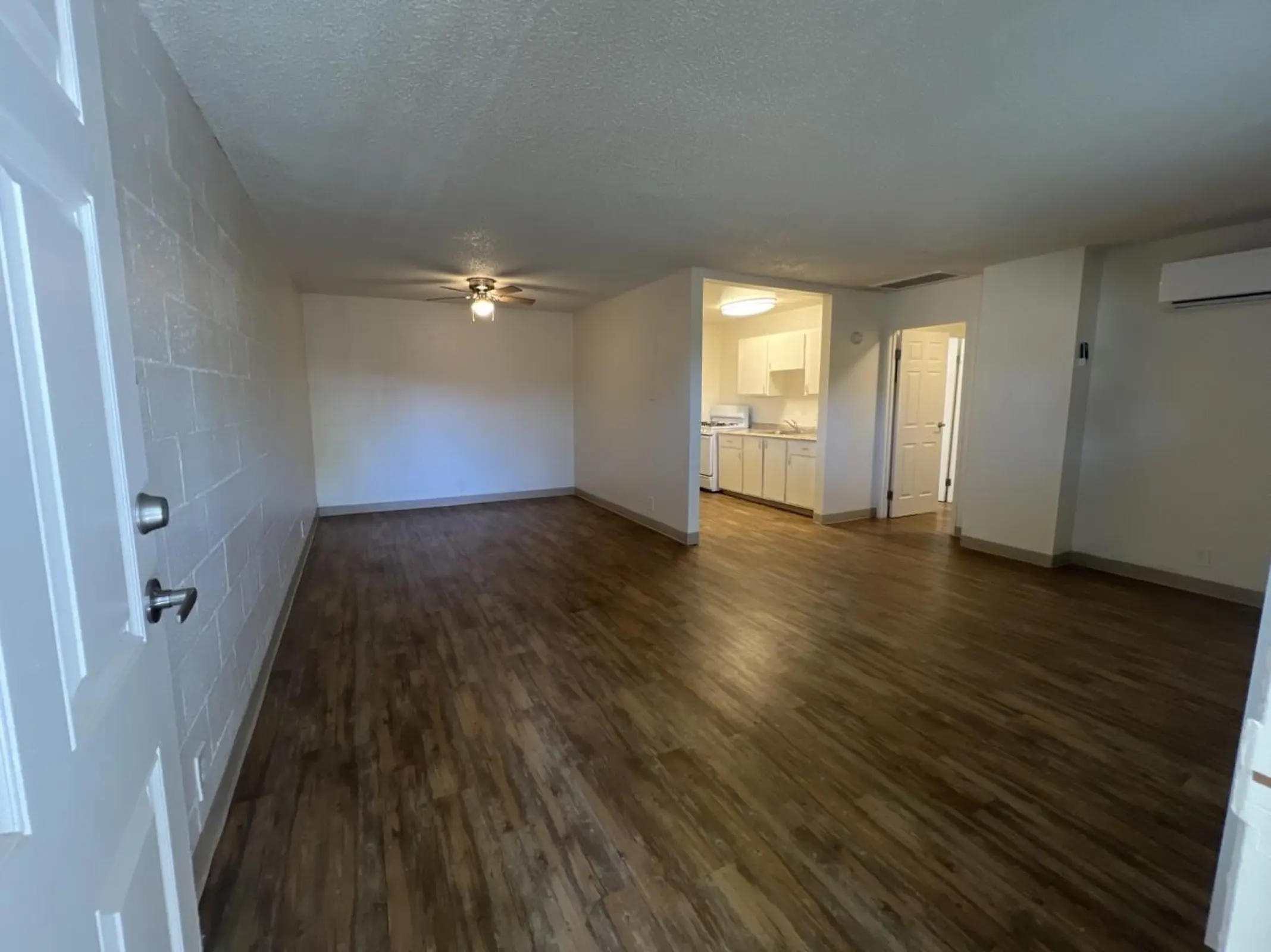 Unfurnished living area with a ceiling fan and adjoining kitchen.