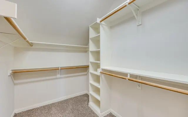 Empty Walk-in Closet An empty walk-in closet with two hanging rods and built-in shelves against the wall.