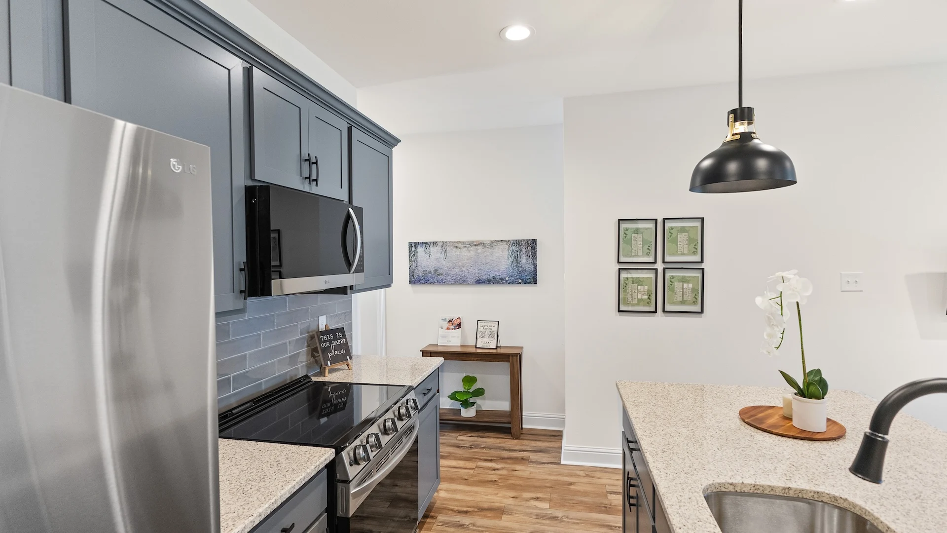 Modern Kitchen Design A contemporary kitchen featuring dark cabinetry, stainless steel appliances, and a granite countertop. There are decorative elements like a potted plant and framed artwork on the walls.