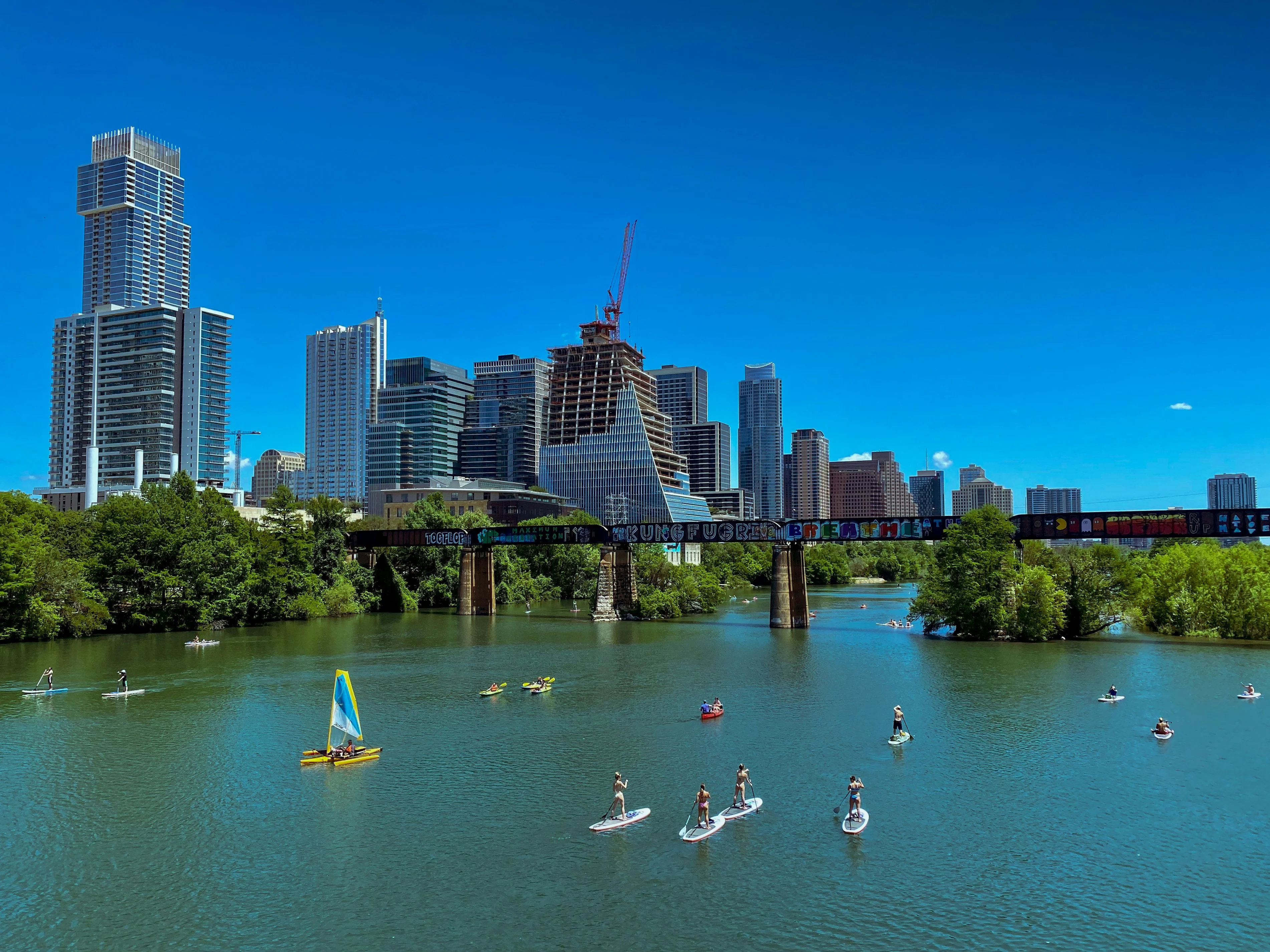 Austin Skyline with Water Activities A vibrant view of the Austin skyline with a clear blue sky, showcasing various water activities on the river.