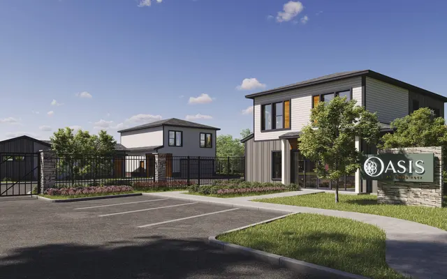 A modern residential property featuring two buildings, lush greenery, and a welcoming sign that reads 'Oasis'.