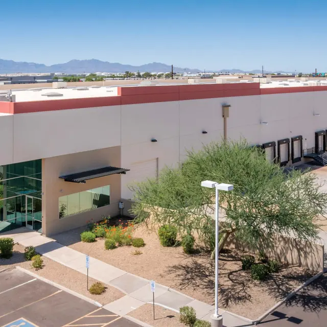Aerial view of a commercial building with a parking lot and surrounding landscaping