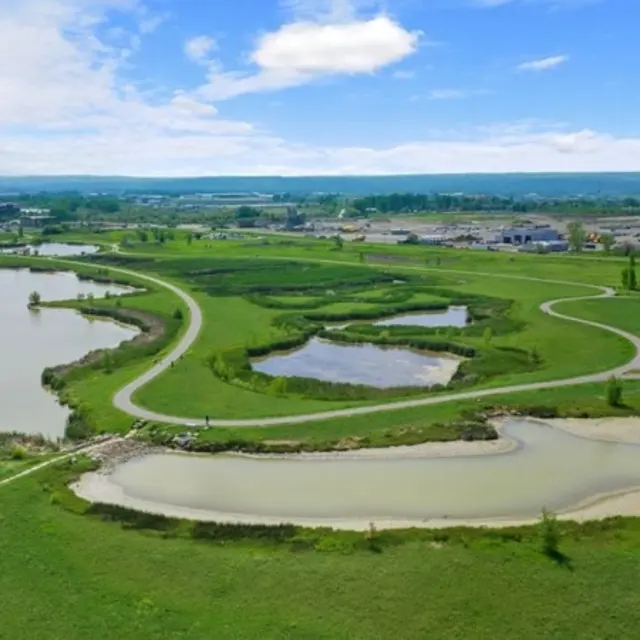 Granite Peak Aerial view of a lush green park with multiple ponds, winding paths, and open fields under a blue sky.