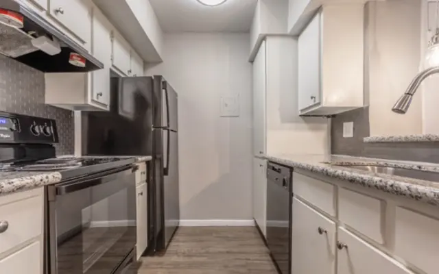 Modern Kitchen Design A modern kitchen featuring stainless steel appliances including a black refrigerator, oven, and microwave. The kitchen has white cabinets with granite countertops and a wooden floor.