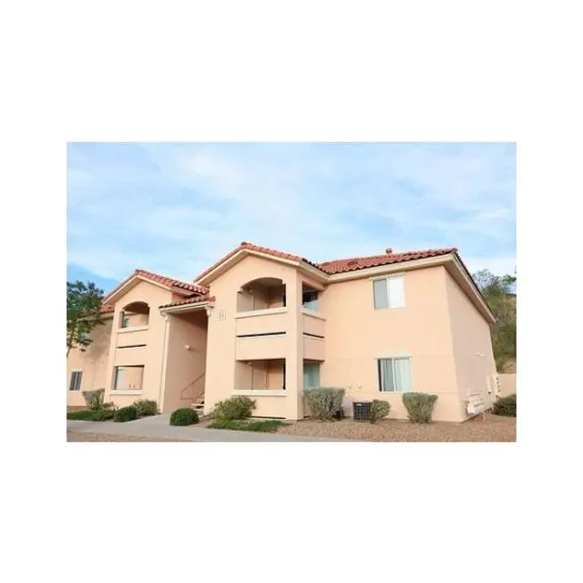 Apartment Building Exterior A light tan apartment building with a terracotta tiled roof, featuring multiple balconies and windows, set against a blue sky.