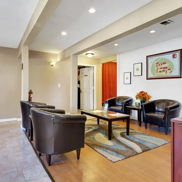 A modern waiting area with brown leather chairs, a coffee table, and decorative wall art.