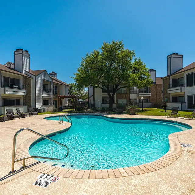 A swimming pool surrounded by apartment buildings on a sunny day.