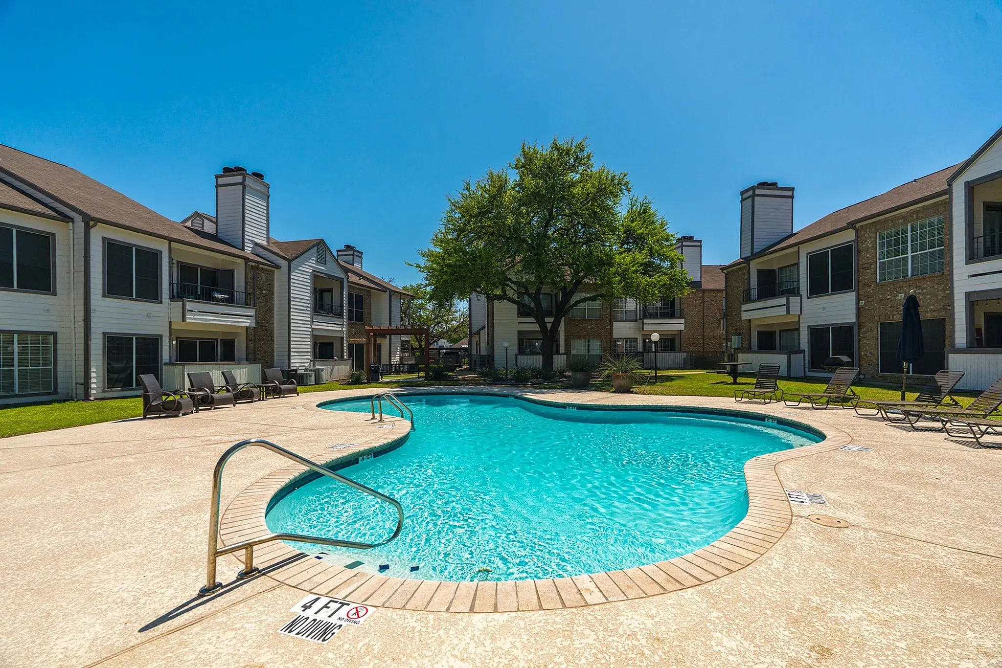 A swimming pool surrounded by apartment buildings on a sunny day.