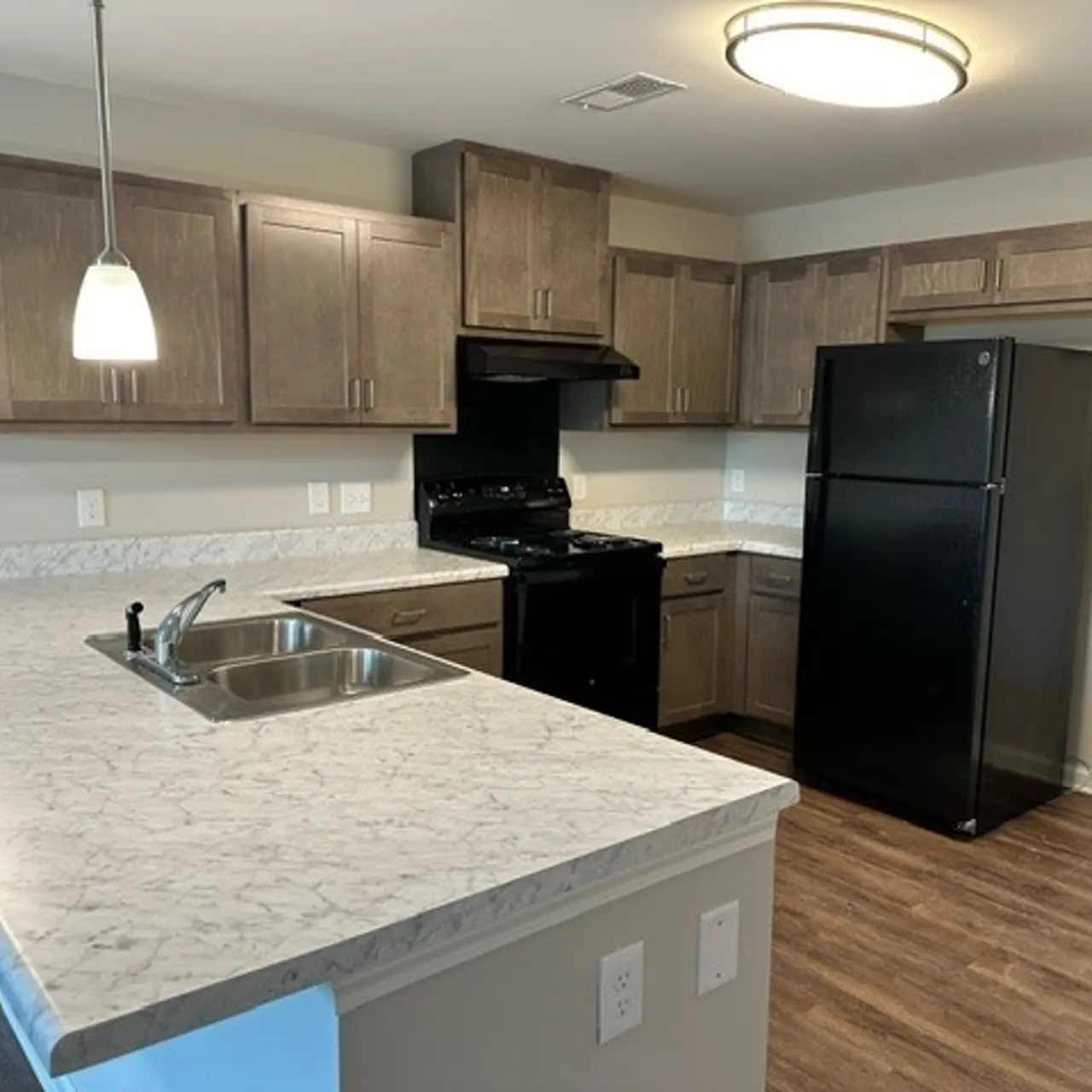 A modern kitchen featuring  wooden cabinets, a black refrigerator, and a black stove.