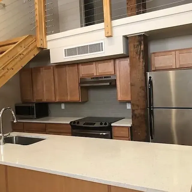 A modern kitchen with wooden cabinets, stainless steel appliances, and a spacious countertop island.