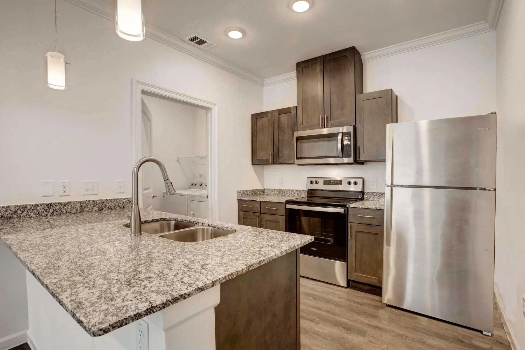 Modern kitchen featuring granite countertops, stainless steel appliances, and dark wood cabinets.