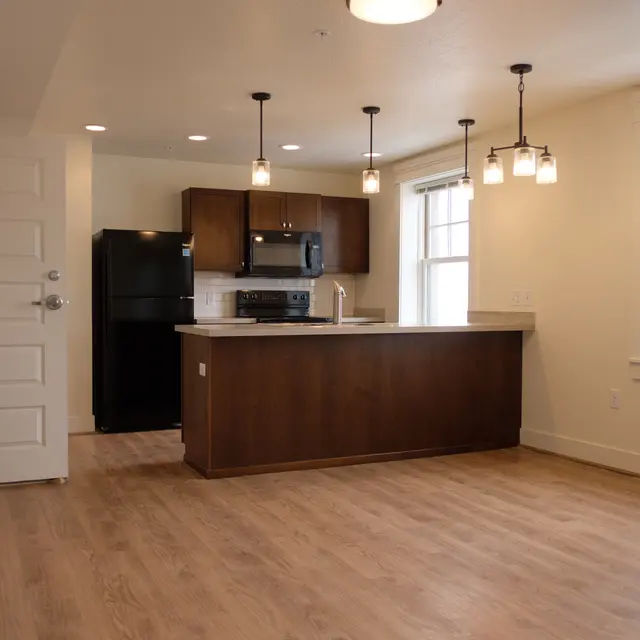 Stylish Modern Apartment Interior Interior of a modern apartment featuring an open layout with a kitchen island, black appliances, and large windows allowing natural light.