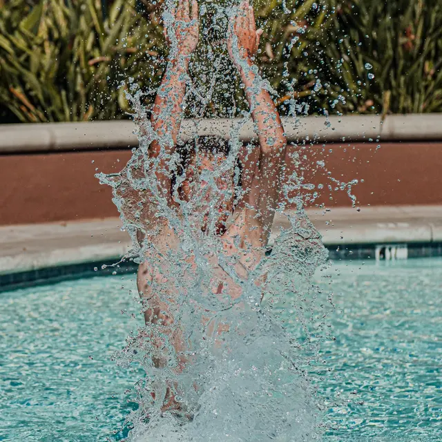 Summer Splash in the Pool A person jumping into a swimming pool creating a large splashing effect.
