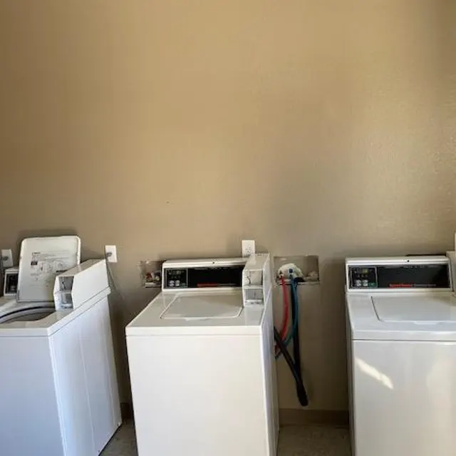 Laundry Room with Washing Machines A laundry room featuring three white washing machines against a beige wall.