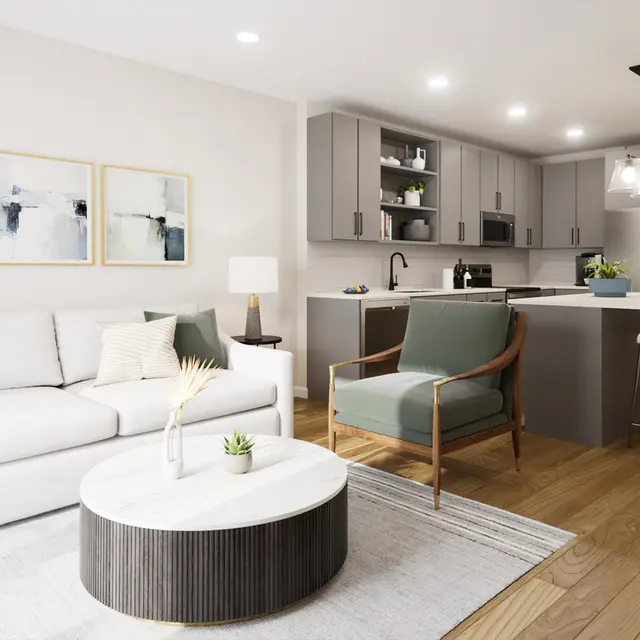 Modern open-concept living space featuring a white sofa, light wood flooring, kitchen island, and stylish decor elements.
