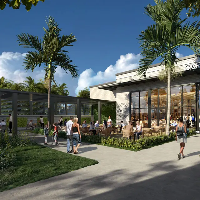 An exterior view of a modern cafe surrounded by greenery and palm trees. There are several people walking on the path and enjoying the outdoor seating area.