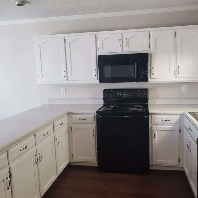 A modern kitchen featuring white cabinetry, black appliances, and a clean countertop.