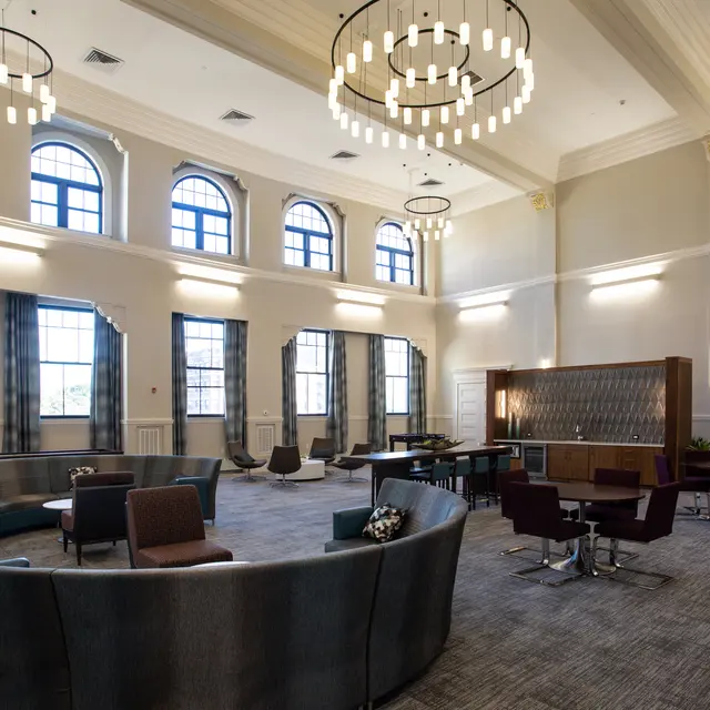 A spacious, elegantly designed interior featuring large windows, stylish furniture, and modern chandeliers.