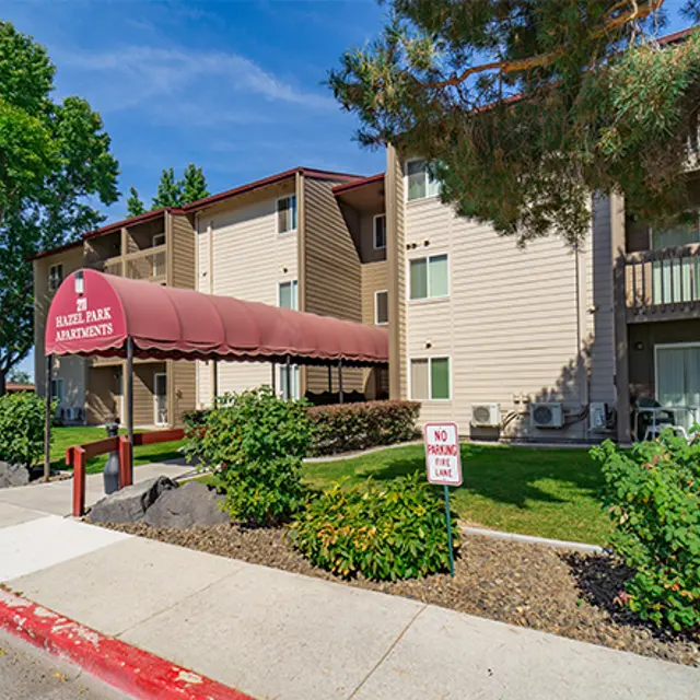 Exterior view of an apartment complex with a sign that reads 'Hassle Free Apartments.'