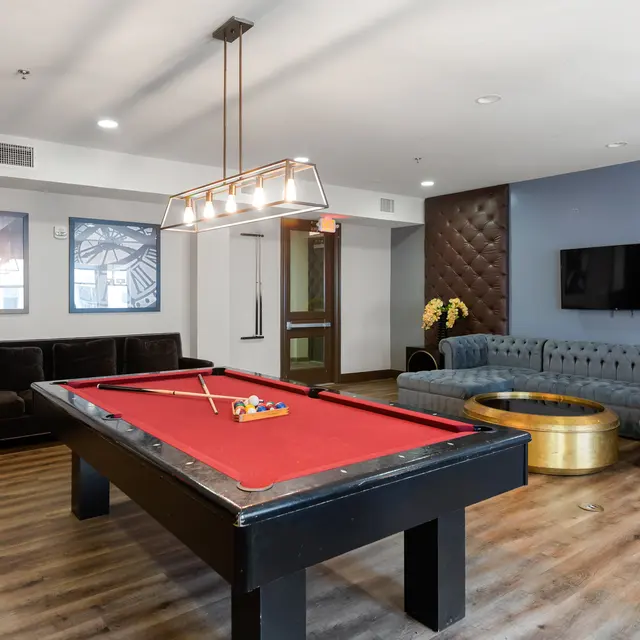 An interior view of a game room featuring a red pool table, comfortable seating areas, and modern decor.