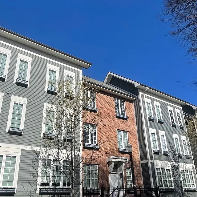 Modern Apartment Complex A row of modern apartment buildings featuring a mix of gray and brick facades under a clear blue sky.