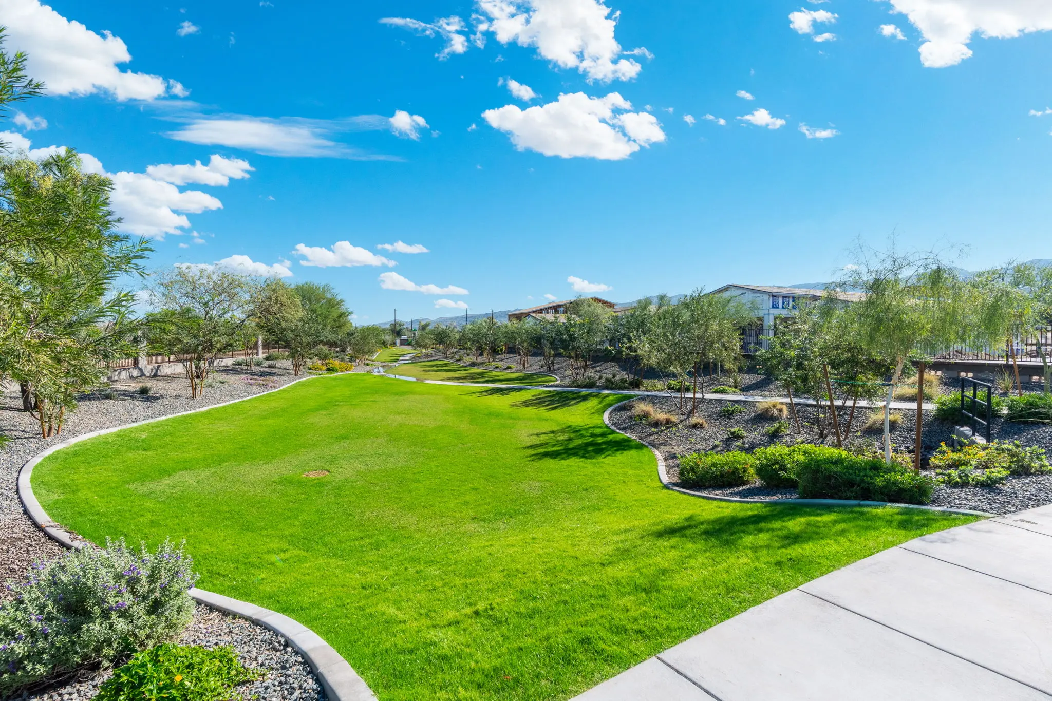 Sunny Park Landscape A sunny park landscape featuring a manicured green lawn bordered by gravel and dotted with trees under a blue sky with clouds.