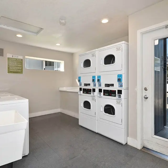 Interior view of a laundry facility with appliances and a door leading outside.