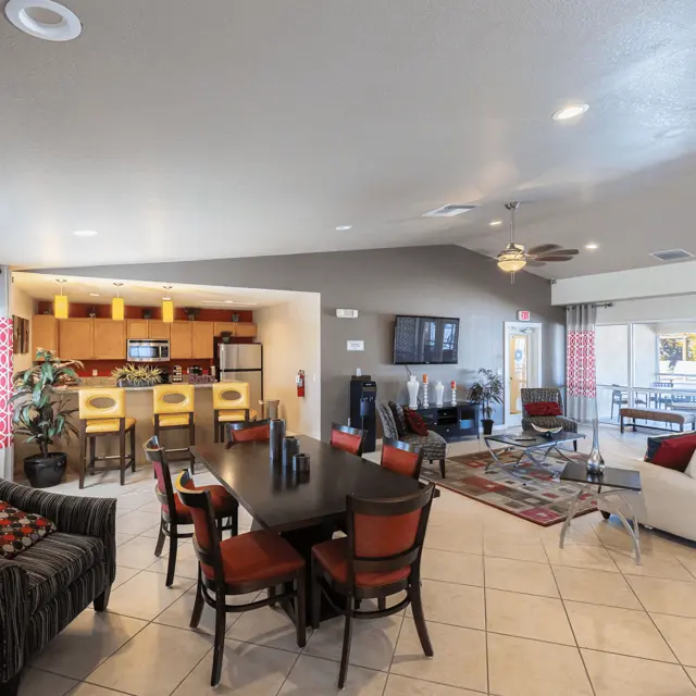 A bright and spacious common area featuring a kitchen, seating areas, and large windows.