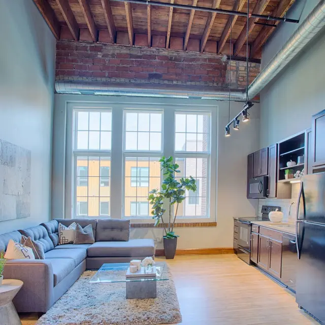 Spacious loft apartment featuring large windows, stainless steel appliances, and rustic ceiling beams at Woodrow in Fargo