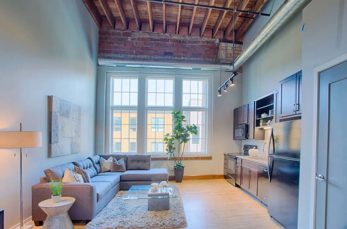 Woodrow Loft Apartment | Fargo, ND Spacious loft apartment featuring large windows, stainless steel appliances, and rustic ceiling beams at Woodrow in Fargo
