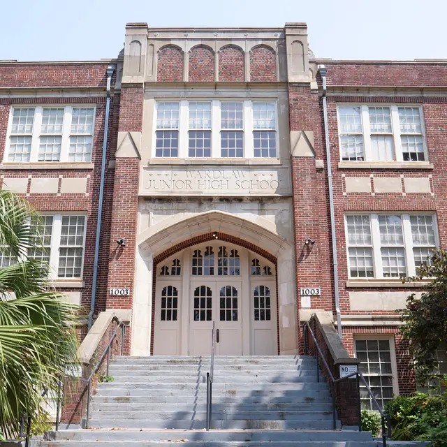 A historic brick school building with large front steps and multiple windows.