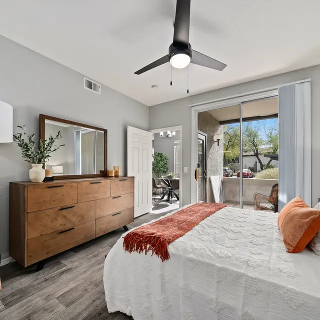 Spacious bedroom with modern furnishings, ceiling fan, and private patio access at Bear Canyon Apartments