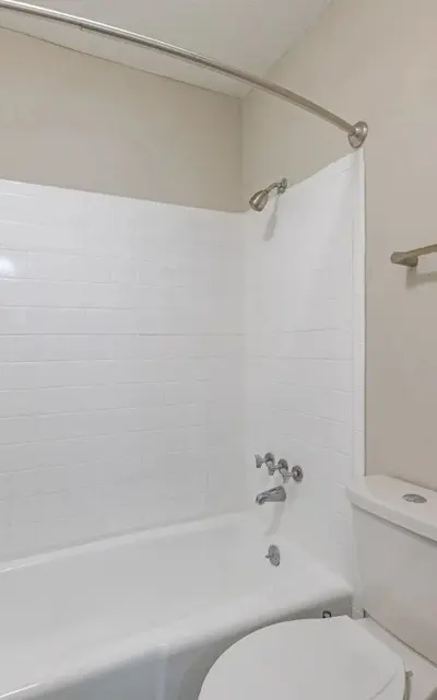 Clean minimalist bathroom with a bathtub, shower, and toilet