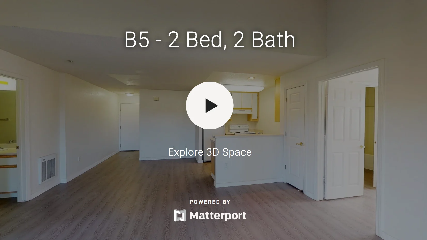 Interior view of a spacious apartment featuring an open layout with a living area and kitchen visible in the background.