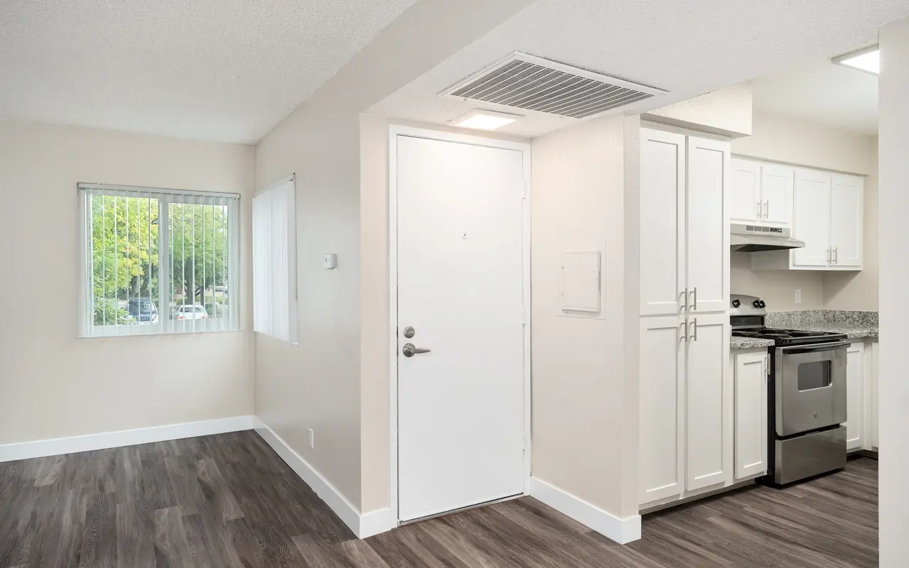 View of a modern apartment interior with an open layout, featuring a kitchen and entrance area.