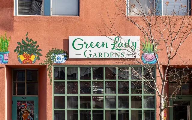 GREEN LADY GARDENS Exterior view of a building featuring the sign 'Green Lady Gardens' with decorative plant illustrations on the wall.