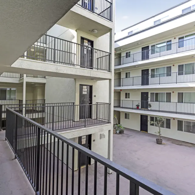 View of a multi-unit apartment complex courtyard with balconies and rooms visible.