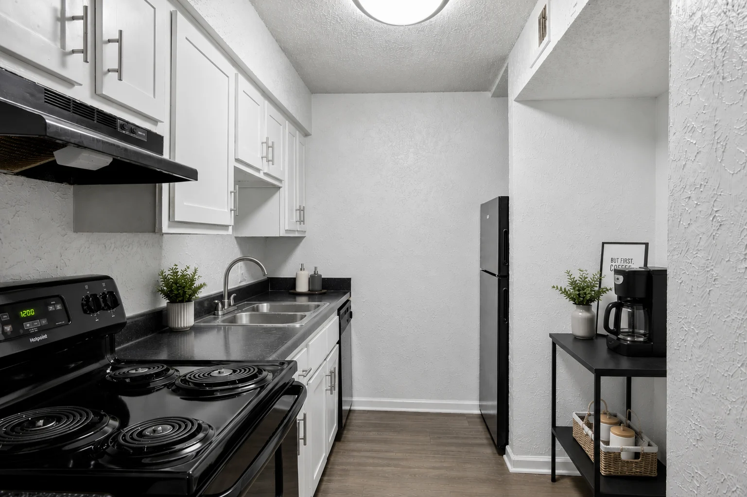A modern kitchen featuring black appliances, white cabinets, and a small dining area.