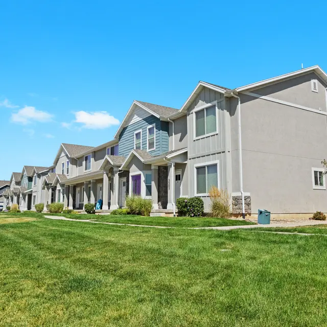 Charming Townhouses in Scenic Setting Row of modern townhouses with green lawn and clear blue sky