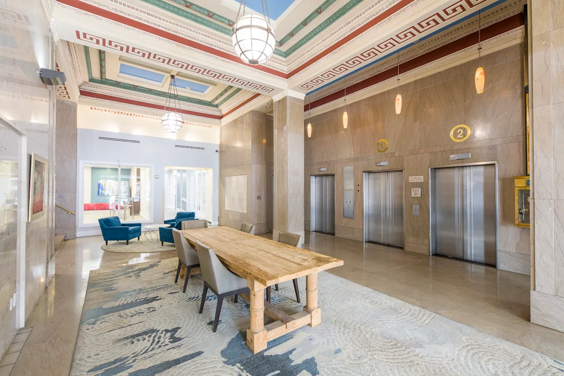 Elevator lobby with seating, large wooden table and elevators in a stylish design.
