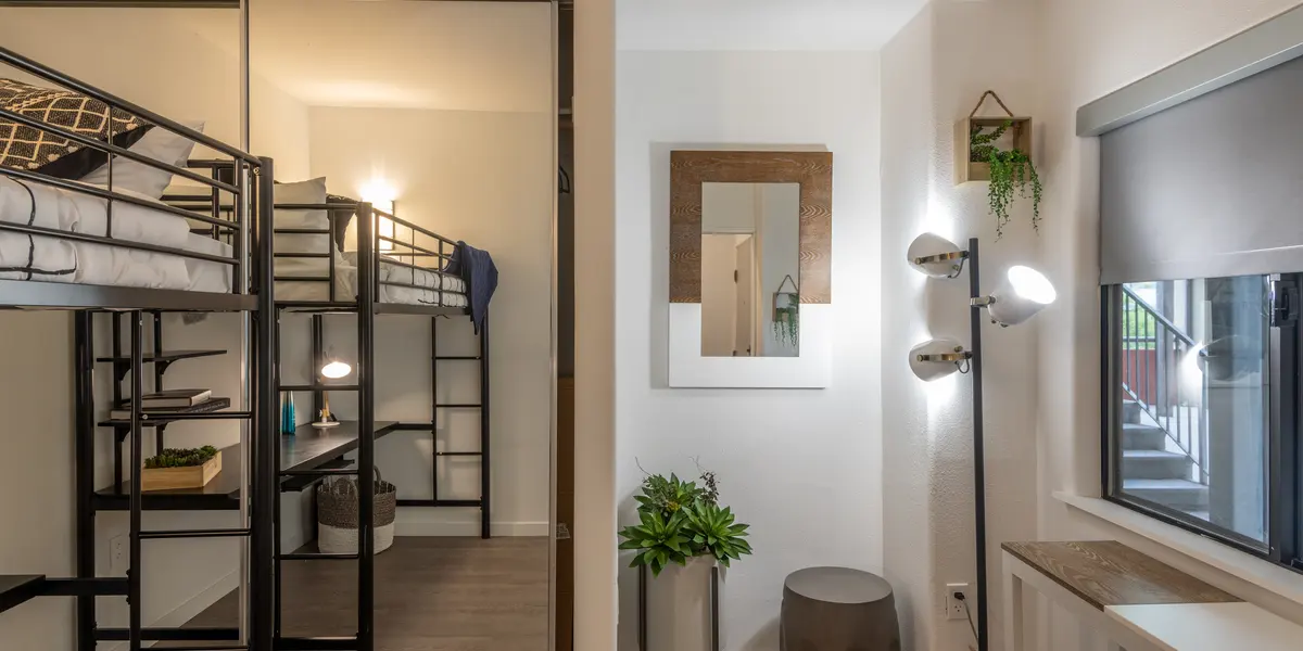 A modern room with a bunk bed on the left side and a stylish sitting area on the right.