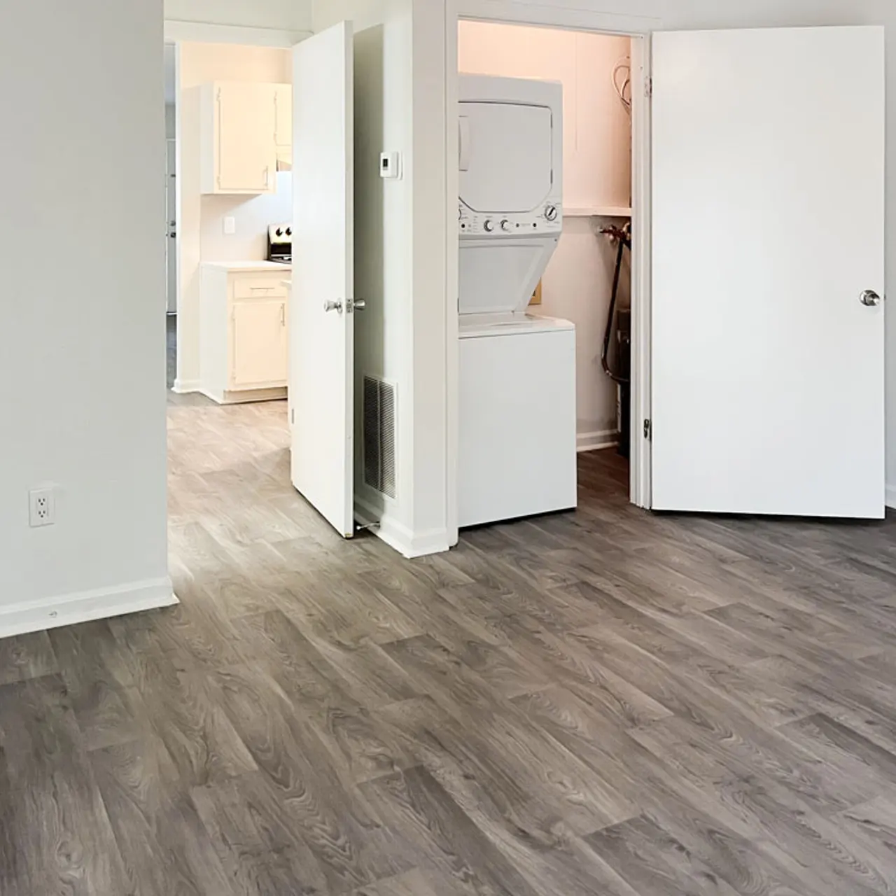 Interior view of an apartment with open doors leading to a laundry area and kitchen.