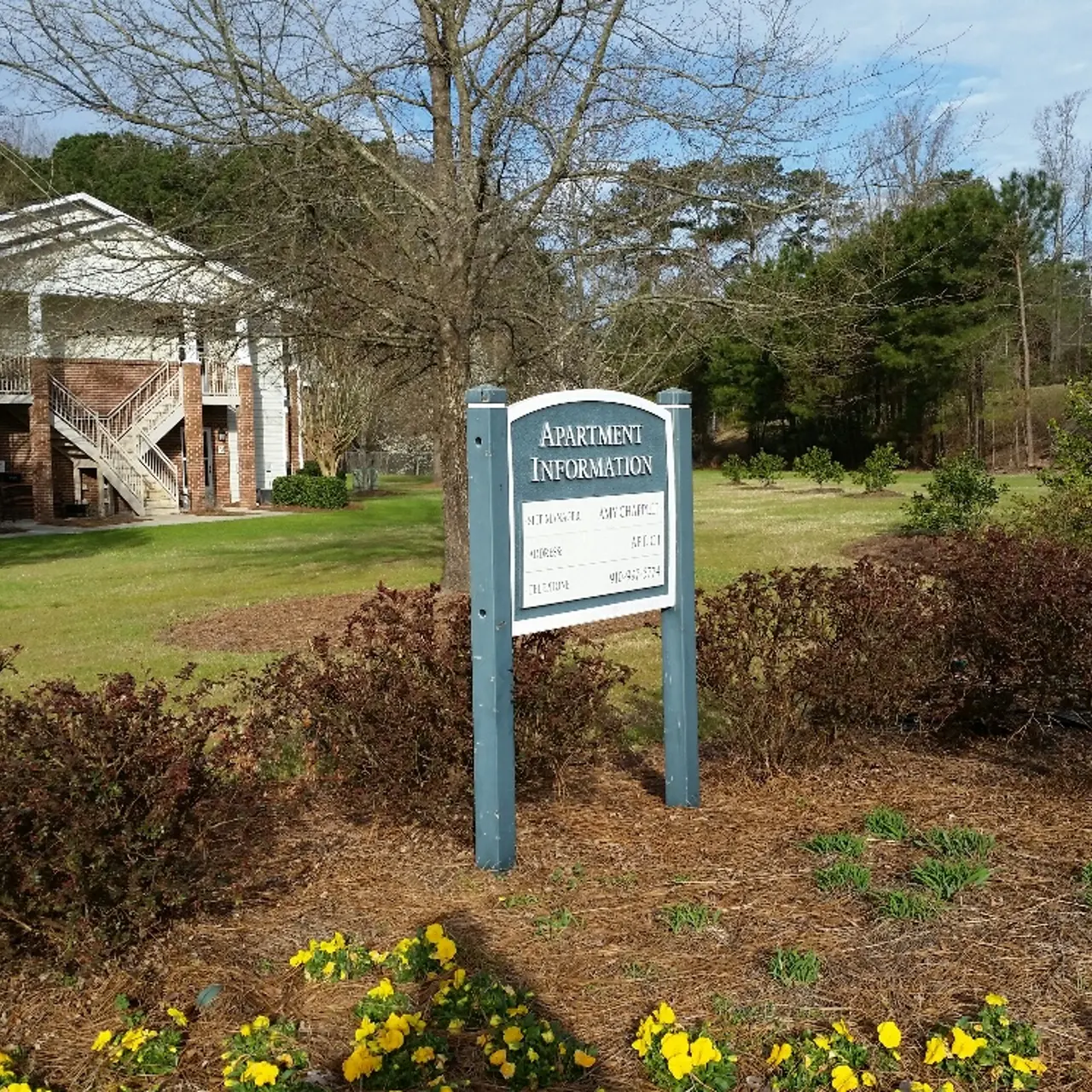 A well-maintained building with a sign indicating 'Information' surrounded by landscaped grounds featuring flowers and trees.